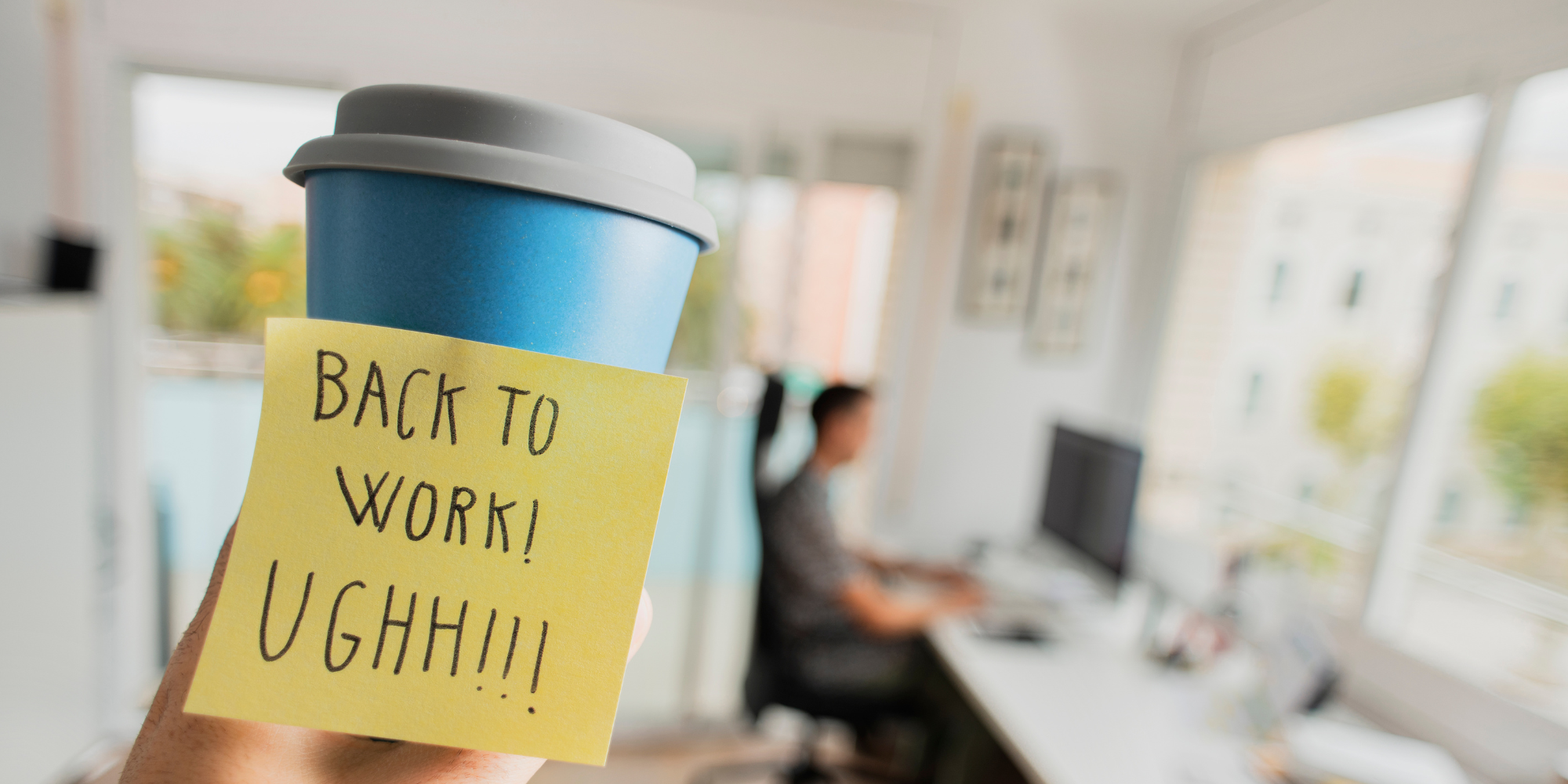 Holding a takeaway coffee cup with a post-it note saying UGH!